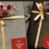 Two wrapped gift boxes with small dried flower accents and gold ribbon