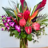 Tropical bouquet with pink orchids and red bird-of-paradise in a glass vase