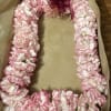 Pink and white carnation lei in a box with a ribbon bow
