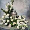White rose floral arrangement around a silver urn