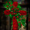 Large cross-shaped arrangement of red roses with glossy green leaves