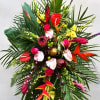 Tall tropical flower arrangement with red, pink, and yellow blooms