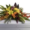 Tropical floral spray with yellow lilies and orange roses on a casket
