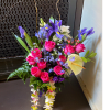 A designer choice bouquet in a vase  adorned with a lei