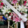 Two pink and white floral wreaths on easels with white ribbons