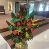 Tropical floral arrangement with red and orange blooms in a gold vase