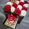 Red and white roses in a black gift box with chocolates and a ribbon