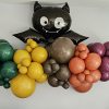 Black cat balloon above a colorful balloon garland on a wall