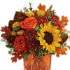 Autumn bouquet with sunflowers, roses, and mums in an orange vase