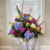 Large floral arrangement in a gold vase with blue, pink, and white blooms