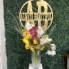Tall vase arrangement of yellow, white, and purple orchids