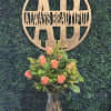 Coral roses in a clear glass vase with yellow filler flowers