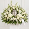 White floral funeral arrangement with a silver urn and ribbon
