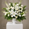White lilies and roses arranged in a white vase