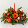 Orange and cream floral centerpiece with a tall red candle