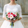 Bride holding a pink and red bouquet with greenery