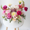 Mixed bouquet of pink, white, and yellow flowers in a white vase