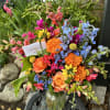 Colorful mixed bouquet in a glass vase with orange roses and blue flowers