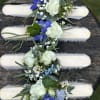 Four floral wrist corsages with white roses and blue flowers on pale bands