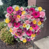 Heart-shaped floral spray with pink, yellow, and purple blooms on an easel