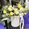 Yellow and white roses arranged in a white hat box with a ribbon