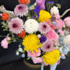 Mixed bouquet of pink, yellow, white, and purple flowers in a vase