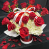 Red roses arranged in a red hatbox with white hydrangeas and ribbon