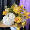 Yellow roses and white hydrangeas in a wrapped bouquet with gold ribbon