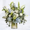 White lilies and roses with blue hydrangeas in a glass vase
