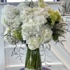 White hydrangea arrangement in a glass vase with pebbles