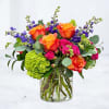 Colorful bouquet of roses, hydrangea, and purple flowers in a glass vase
