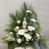 White floral arrangement with a small statue of the Virgin Mary