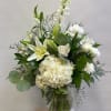 White floral arrangement in a clear glass vase with lilies and hydrangea
