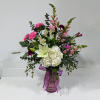 Mixed pink and white flowers in a glass vase with a purple ribbon