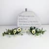 Memorial stone with white flowers and greenery arranged at the base