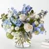 Blue and white bouquet of roses and mixed blooms in a glass vase