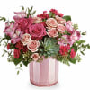 Pink and peach roses in a pink glass vase with greenery