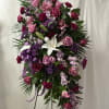 Standing floral spray with pink and purple flowers and a white lily