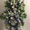 Large standing floral spray with white and blue flowers and a ribbon tribute