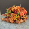 Orange and burgundy floral arrangement in a wicker basket