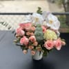 Pink roses and white orchids arranged in a white vase