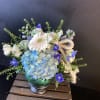 Blue and white floral arrangement in a glass vase