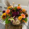Colorful mixed floral arrangement in a wooden container with orange and purple blooms