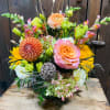 Colorful floral arrangement with peach roses, yellow blooms, and pink snapdragons in a vase
