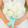 Bride holding a white rose bouquet with a turquoise ribbon