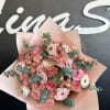 Pink and white bouquet of roses and ranunculus wrapped in blush paper