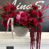 Large red rose arrangement in a silver textured vase with pink ribbon