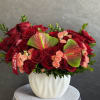 Red roses and peach spray roses in a white vase with anthuriums