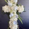 White floral cross arrangement on an easel with roses and orchids