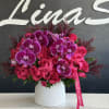 Pink roses and purple orchids arranged in a white vase